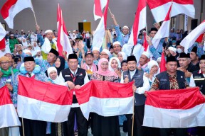 Sambut Kedatangan Jemaah Haji Kloter 87, Gubernur Khofifah Potong Tumpeng dan Bagikan Bendera Merah