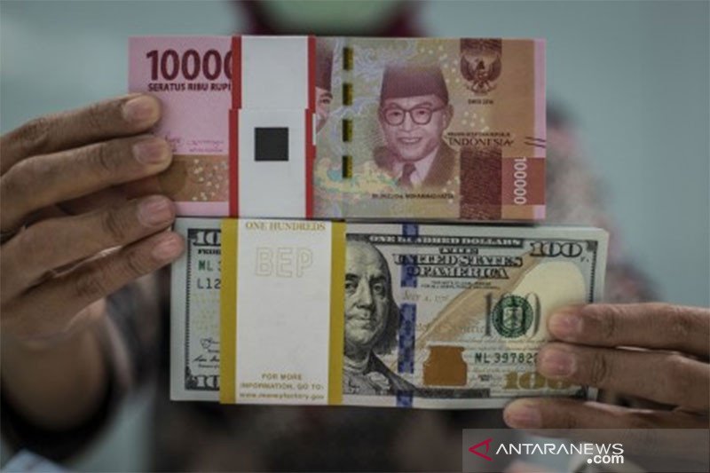 Ilustrasi: Karyawan menunjukkan uang rupiah dan dolar AS di Kantor Cabang Plaza Mandiri, Jakarta. ANTARA FOTO/Aprillio Akbar/wsj.

