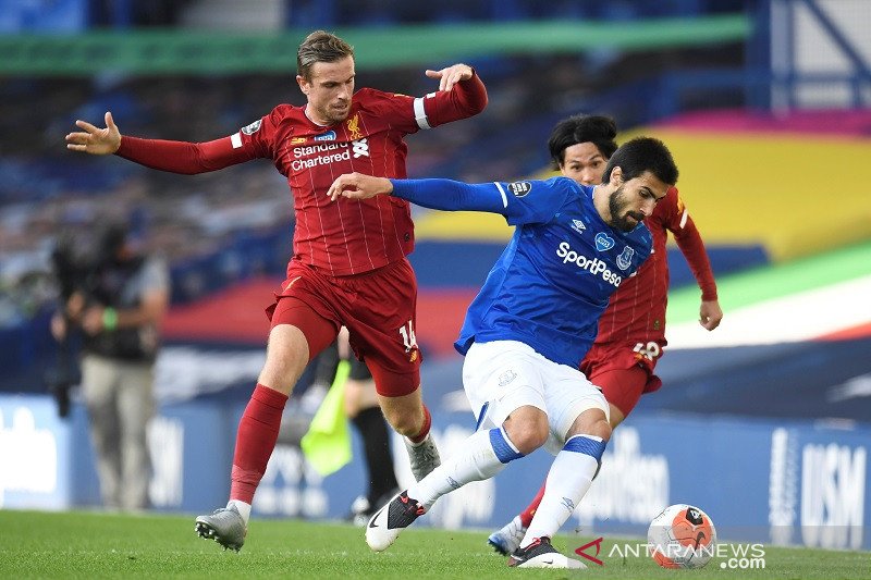 Gelandang Everton Andre Gomes (kanan) berusaha menjaga penguasaan bola dari upaya rebutan kapten Liverpool Jordan Henderson dalam Derbi Merseyside untuk laga lanjutan Liga Inggris tanpa penonton karena pandemi COVID-19 di Stadion Goodison Park, Liverpool,