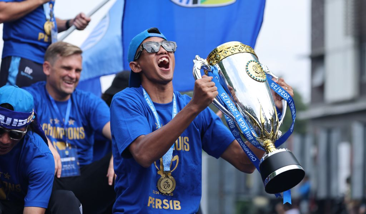 ek PERSIB, Kakang Rudianto mengangkat trofi Liga 1 2024/25 pada konvoi juara di Kota Bandung, Minggu, 25 Mei 2025. (PERSIB.co.id/Barly Isham)
