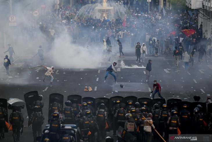 Pengunjuk rasa melempar batu ke arah polisi saat unjuk rasa menolak Undang-undang Cipta Kerja di depan Gedung Negara Grahadi, Surabaya, Jawa Timur, Kamis (8/10/2020). Aksi yang dikuti ribuan orang dari berbagai elemen mahasiswa dan buruh tersebut berakhir