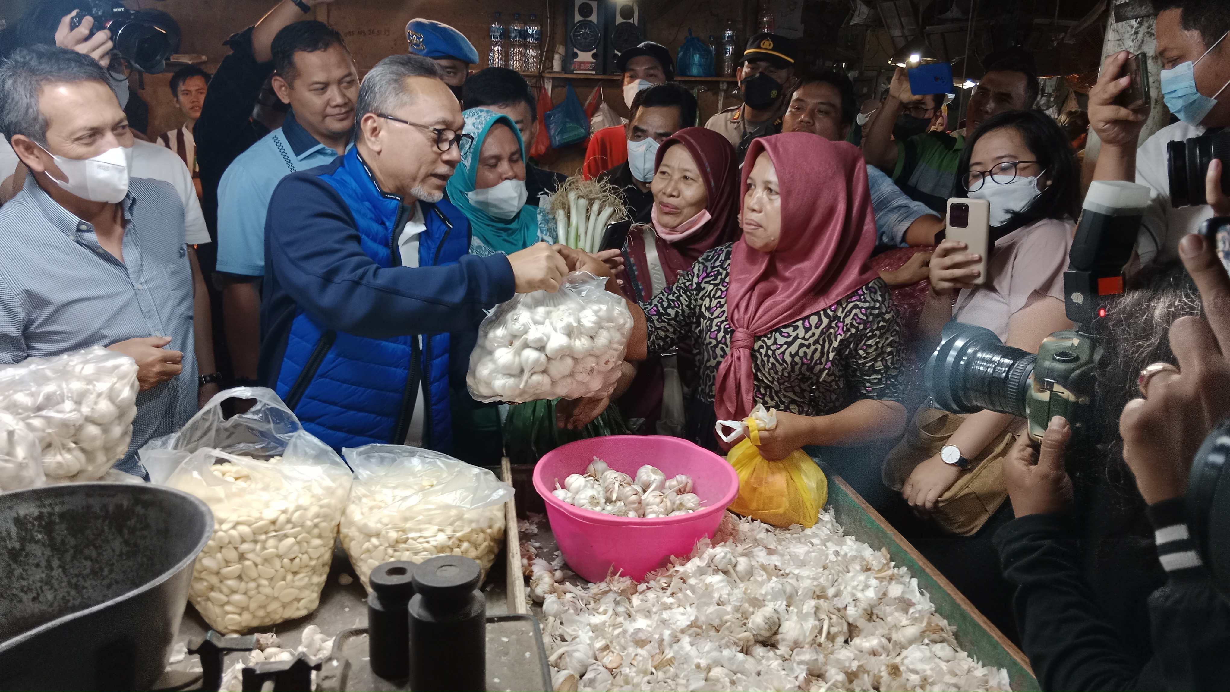 Menteri Perdagangan Zulkifli Hasan membelanjakan bawang putih untuk diberikan dengan gratis kepada pembeli saat melakukan kunjungan di Pasar Keputran Surabaya, Jawa Timur, Sabtu (30/7/2022). foto: prasetyo