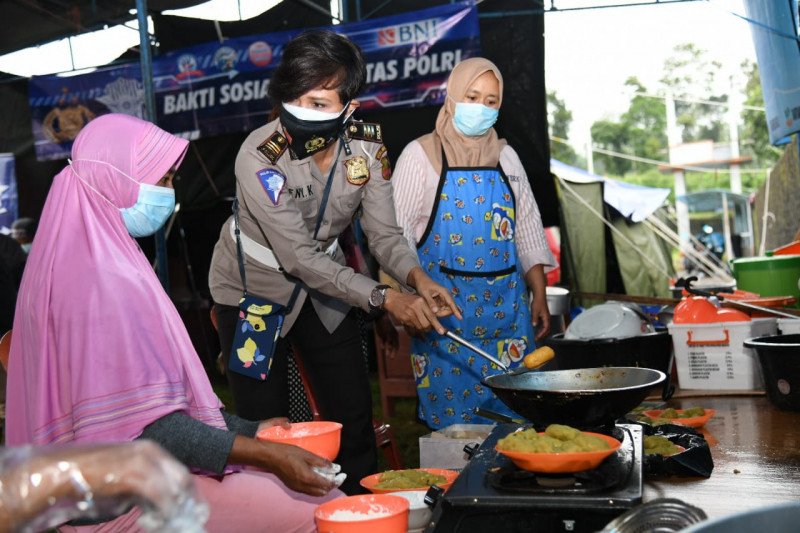 Polwan Korlantas Polri AKP Eny (tengah) membantu para ibu-ibu memasak di dapur umum di Desa Klakah, Kabupaten Boyolali, Jawa Tengah. (ANTARA/ HO-NTMC Polri)
