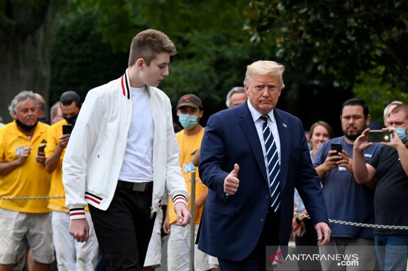 Presiden Amerika Serikat Donald Trump dan putranya Barron berjalan menuju Gedung Putih dari Marine One di Washington, Amerika Serikat, Minggu (16/8/2020). REUTERS/Erin Scott/WSJ/djo (REUTERS/ERIN SCOTT)