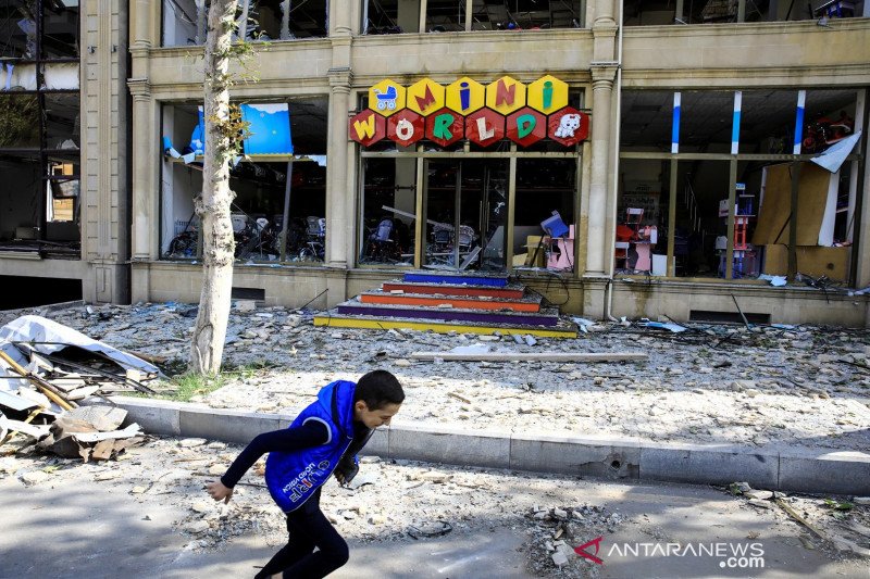 Seorang anak lelaki berlari melewati toko yang hancur di lokasi ledakan di Kota Ganja, Azerbaijan, Minggu (11/10/2020), yang terkena serangan roket saat terjadi pertempuran atas wilayah Nagorno-Karabakh yang memisahkan diri. ANTARA FOTO/REUTERS/Umit Bekta