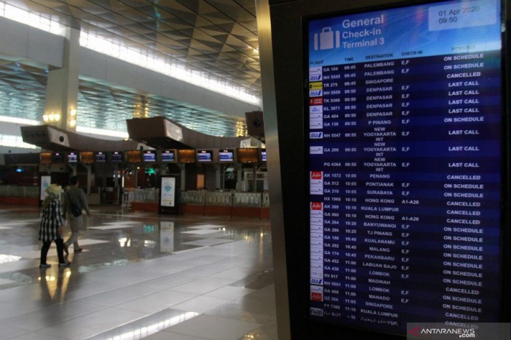 TIDAK ADA MUDIK: Penumpang melintas di samping monitor jadwal penerbangan yang memperlihatkan pengumuman pembatalan penerbangan di Terminal 3 Bandara Soekarno Hatta, Tangerang, Banten, Rabu (1/4/2020). ANTARA FOTO/Muhammad Iqbal/hp.