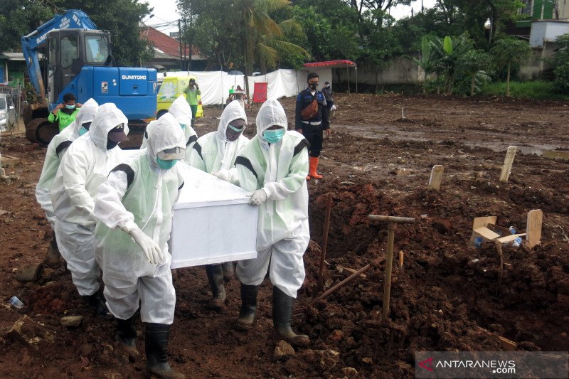 Petugas pemakaman mengangkat peti jenazah untuk dimakamkan dengan protokol COVID-19 di TPU Srengseng Sawah II, Jagakarsa, Jakarta Selatan, Selasa, (2/2/2021). Kepala Pusat Data dan Informasi (Kapusdatin) Dinas Pertamanan dan Pemakaman DKI Jakarta Ivan Mur