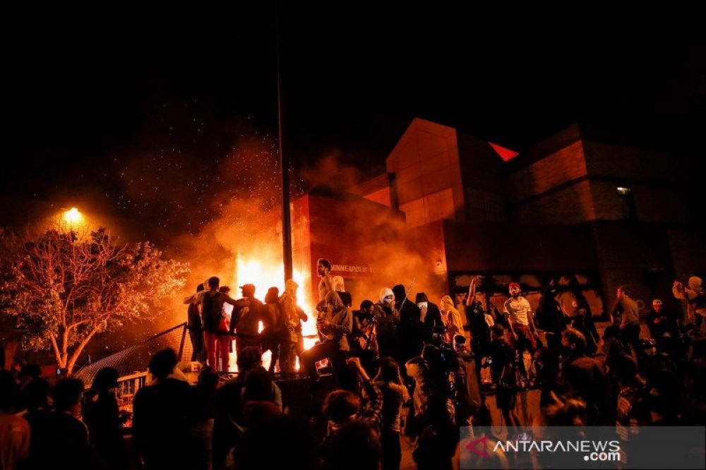 Para pengunjuk rasa berkumpul di sekitar kantor polisi Minneapolis yang terbakar saat demonstrasi setelah seorang polisi kulit putih tertangkap video amatir menekan lututnya ke leher pria Afrika-Amerika George Floyd, yang kemudian meninggal di sebuah ruma