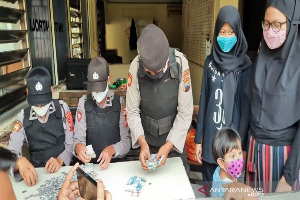  Seorang siswa SMP dan kakaknya saat mendatangi menyerahkan dana hasil celengannya selama setahun untuk membantu penanganan pandemi COVID-19, kepada petugas polisi, di Mapolresta Surakarta, Senin (20/4/2020) (HMP/antara) 