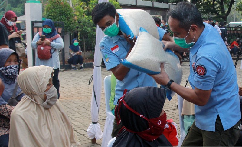 Petugas Kementerian Sosial memberikan beras kepada warga penerima paket sembako bantuan pemerintah di Rawa Buntu, Tangerang Selatan, Banten, Selasa (23/6/2020). ANTARA FOTO/Muhammad Iqbal/pras.

