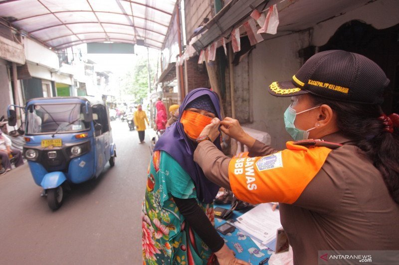 Petugas memakaikan masker kepada warga yang melanggar protokol kesehatan di kawasan Jalan Menteng Atas, Jakarta, Selasa (29/9/2020).(ANTARA FOTO/Reno Esnir/foc.)
