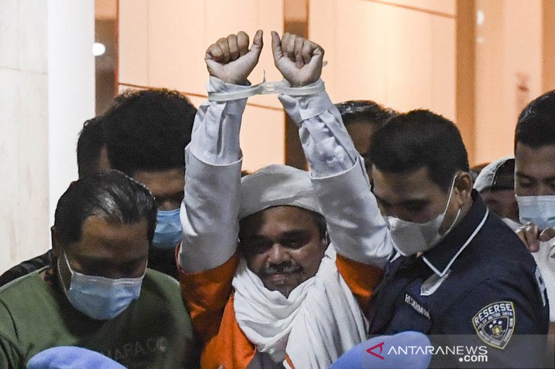 Imam Besar Front Pembela Islam (FPI) Habib Rizieq Shihab (tengah) berjalan menuju mobil tahanan usai diperiksa di Mapolda Metro Jaya, Jakarta, Minggu (13/12/2020) dini hari. ANT