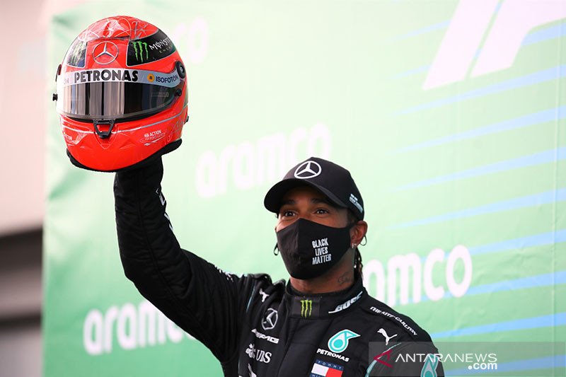 Pebalap tim Mercedes Lewis Hamilton melakukan selebrasi dengan mengangkat helm milik Michael Schumacher setelah memenangi Grand Prix Eifel di Sirkuit Nurburgring, Jerman (11/10/2020). ANTARA/REUTERS/Pool/Bryn Lennon/aa. (Pool via REUTERS/BRYN LENNON)

