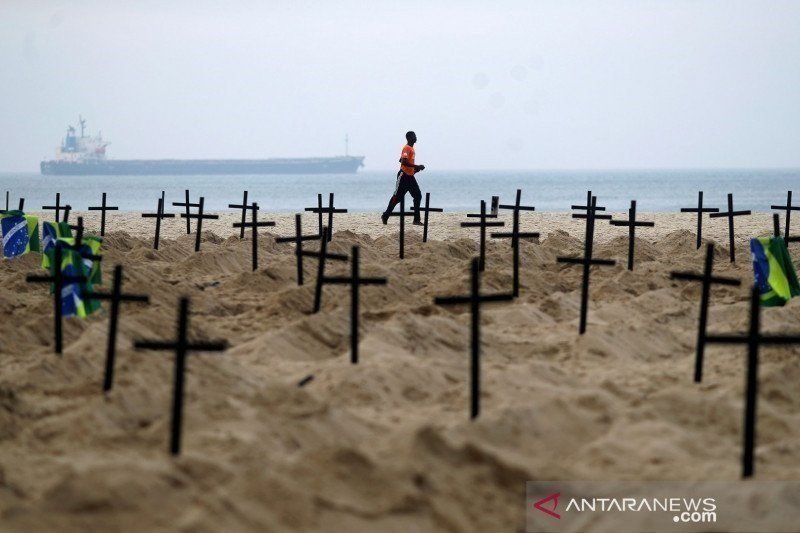 Seorang warga berlari di Rio de Janeiro, Brazil, Kamis (11/6/2020), melewati ratusan makam yang digali oleh aktivis LSM Rio de Paz di pantai Copacabana untuk menyimbolkan warga yang meninggal dunia akibat penyakit virus corona (COVID-19). (REUTERS/Pilar O